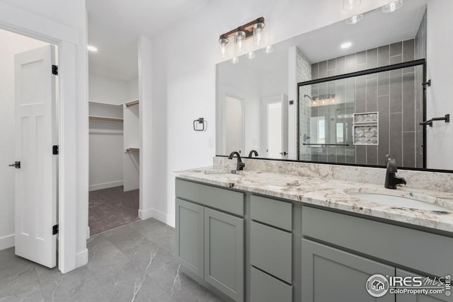 bathroom with double vanity, a spacious closet, a stall shower, and a sink