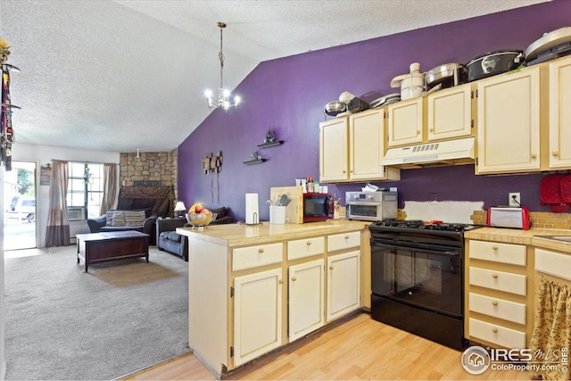 kitchen featuring light hardwood / wood-style floors, pendant lighting, vaulted ceiling, black appliances, and a textured ceiling