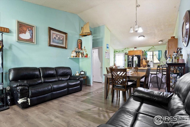 living room with lofted ceiling, an inviting chandelier, wood-type flooring, and a textured ceiling