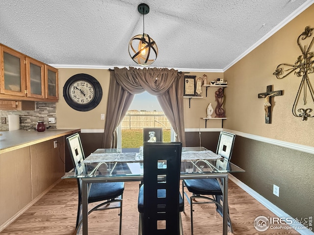 dining area with lofted ceiling, crown molding, a textured ceiling, and wood finished floors