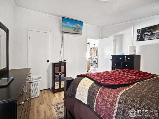 bedroom with ornamental molding and light wood finished floors