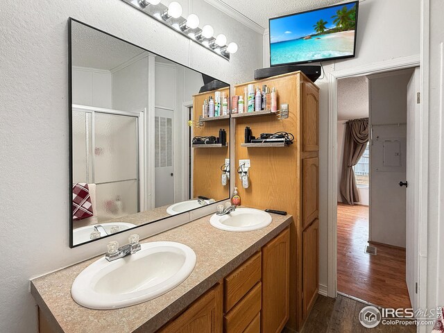 bathroom with a stall shower, crown molding, a textured ceiling, and a sink