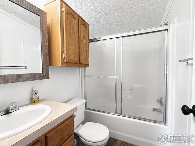 full bathroom featuring a textured ceiling, toilet, shower / bath combination with glass door, and vanity