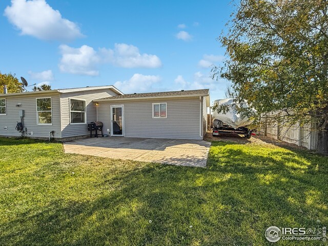 rear view of house with a patio, a lawn, and fence