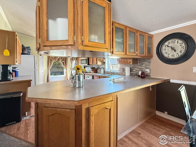 kitchen featuring a peninsula, ornamental molding, and brown cabinetry