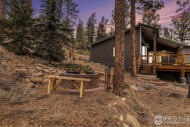 property exterior at dusk with a deck and a fire pit