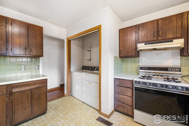 kitchen featuring white gas stove, washing machine and clothes dryer, and decorative backsplash