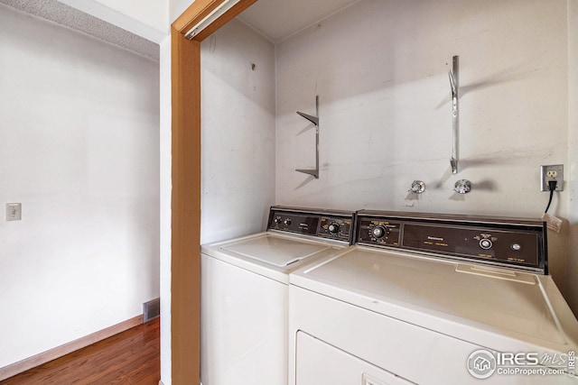 laundry area featuring washing machine and clothes dryer and hardwood / wood-style floors