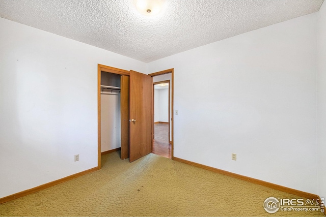 unfurnished bedroom with carpet floors, a textured ceiling, and a closet