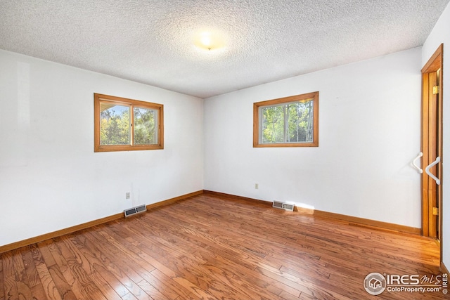 spare room with wood-type flooring and a textured ceiling