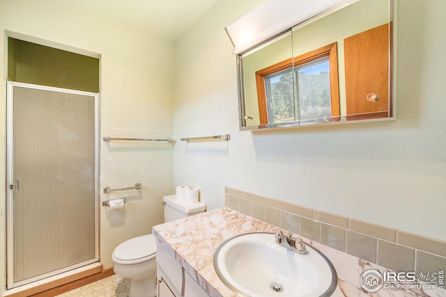 bathroom featuring tile patterned flooring, a shower with shower door, vanity, and toilet