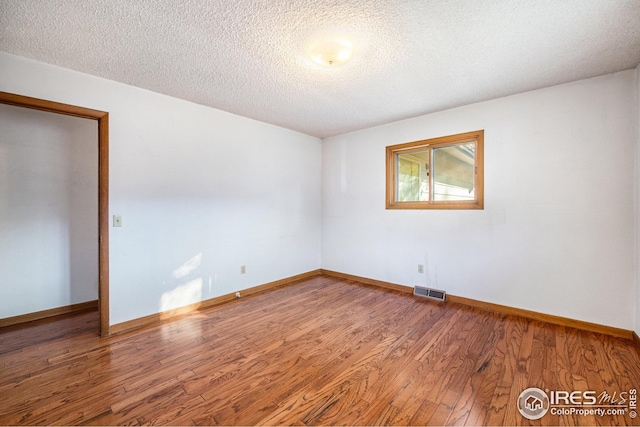 spare room featuring hardwood / wood-style floors and a textured ceiling