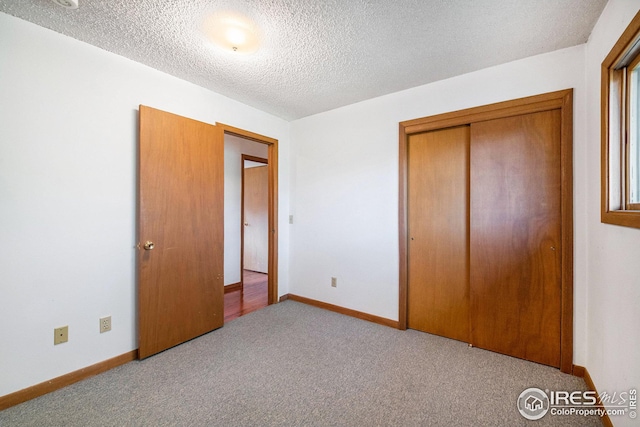 unfurnished bedroom featuring light colored carpet, a textured ceiling, and a closet