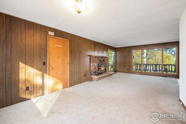 living room featuring a fireplace, wooden walls, carpet, and a textured ceiling