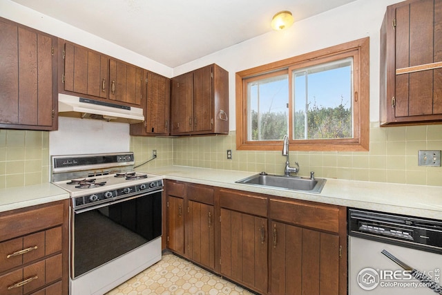 kitchen featuring dishwasher, backsplash, sink, and white range oven