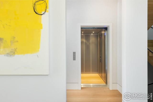 hall with hardwood / wood-style floors and elevator