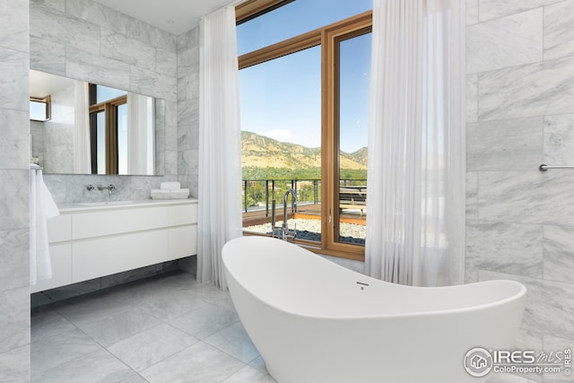 bathroom featuring a bathing tub, a mountain view, tile walls, and vanity