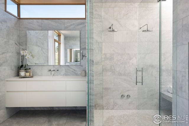 bathroom featuring walk in shower, vanity, tile walls, and plenty of natural light