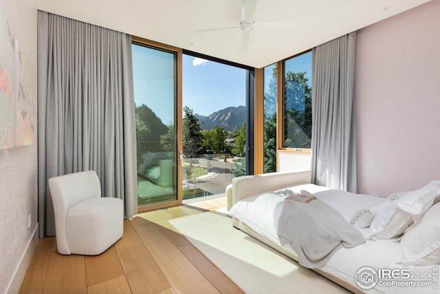 bedroom with a mountain view, ceiling fan, floor to ceiling windows, and hardwood / wood-style floors