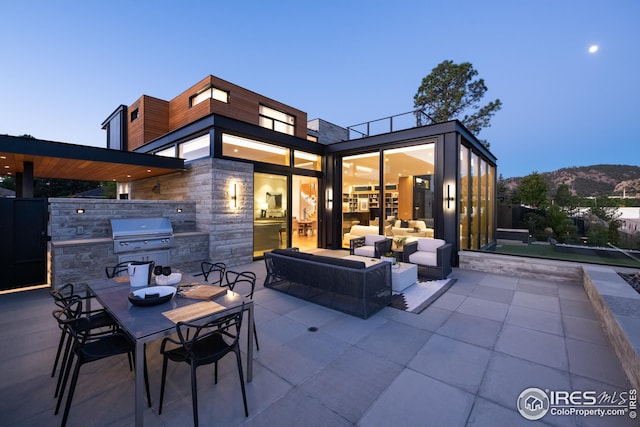 patio terrace at dusk featuring area for grilling and a mountain view