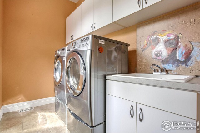 washroom with washer and clothes dryer, light tile patterned floors, cabinets, and sink