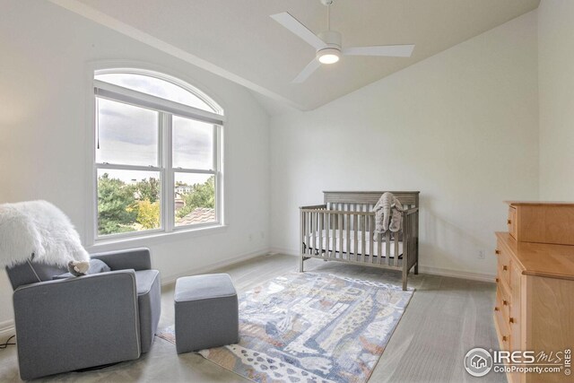 carpeted bedroom with a crib, ceiling fan, and lofted ceiling