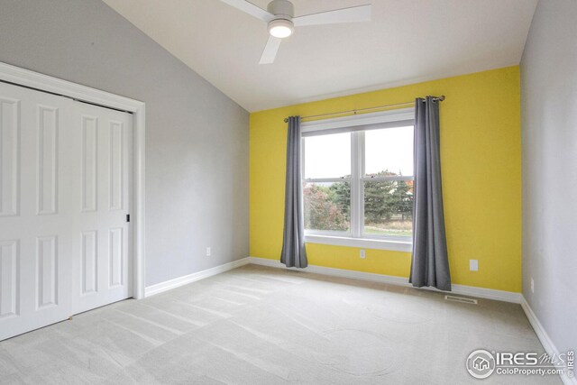 spare room featuring ceiling fan, light colored carpet, and lofted ceiling