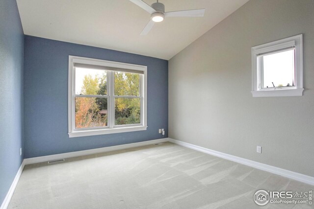 empty room with light colored carpet, vaulted ceiling, and ceiling fan