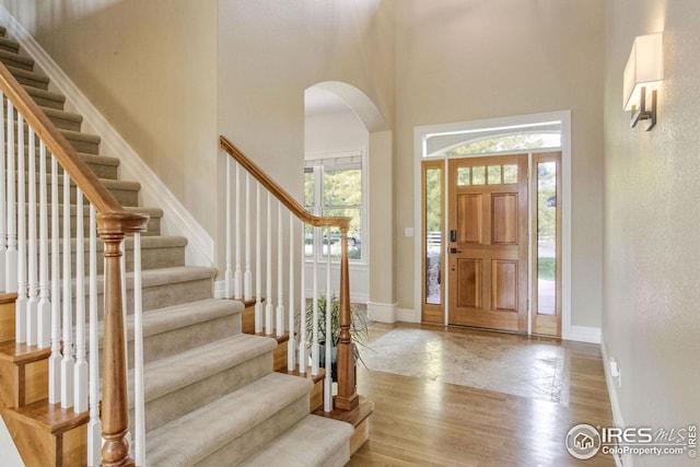 foyer entrance with a towering ceiling and light hardwood / wood-style floors