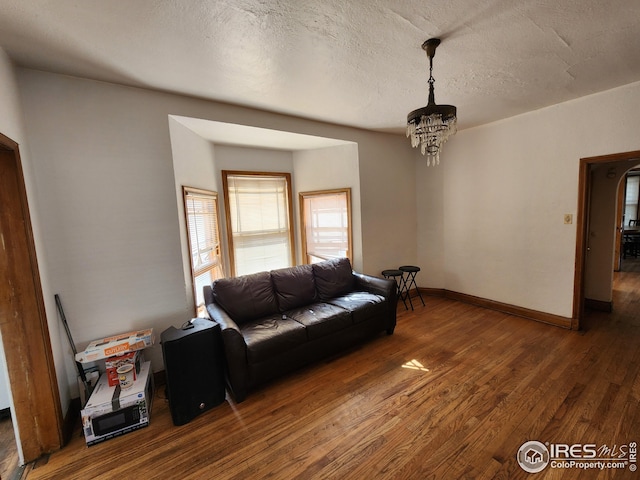 living room featuring dark wood-type flooring, a chandelier, and a textured ceiling