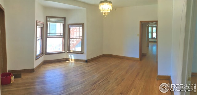 empty room with a notable chandelier and hardwood / wood-style flooring