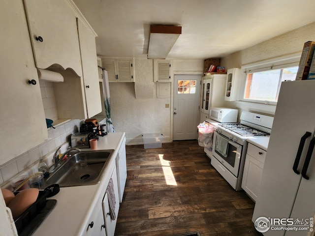 kitchen with white cabinets, dark hardwood / wood-style floors, sink, and white appliances