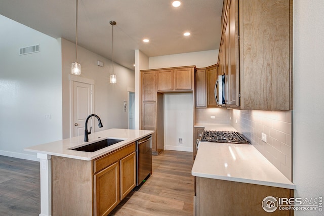 kitchen with light hardwood / wood-style flooring, stainless steel appliances, sink, and a center island with sink