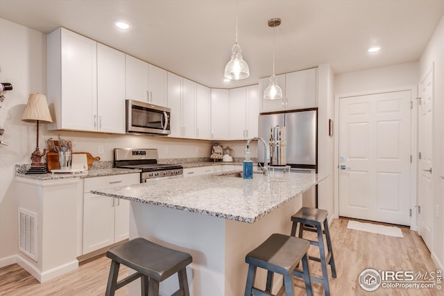 1135 Hummingbird Cir, Longmont, CO 80501 - kitchen featuring white cabinets, a sink, a breakfast bar area, stainless steel appliances, and light wood-type flooring