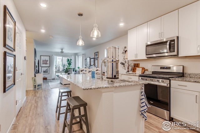 1135 Hummingbird Cir, Longmont, CO 80501 - kitchen with white cabinets, stainless steel appliances, recessed lighting, and light wood-style floors