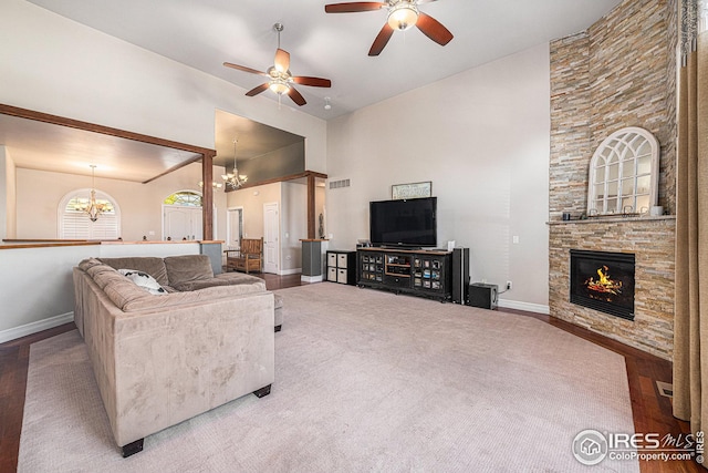 living room featuring lofted ceiling, wood-type flooring, a fireplace, and ceiling fan with notable chandelier