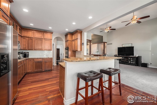 kitchen with decorative backsplash, dark hardwood / wood-style flooring, kitchen peninsula, and stainless steel fridge with ice dispenser