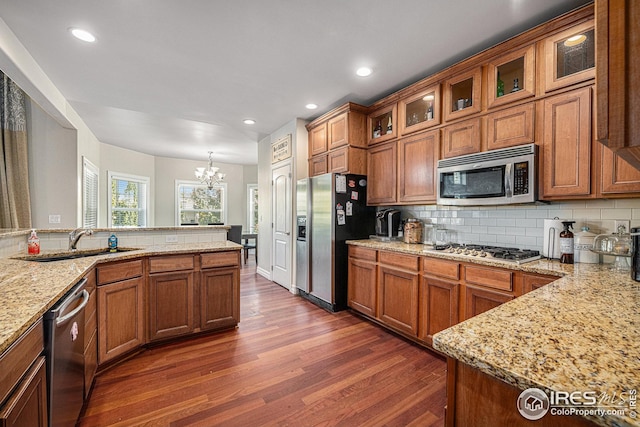 kitchen featuring dark hardwood / wood-style floors, stainless steel appliances, sink, light stone countertops, and a chandelier