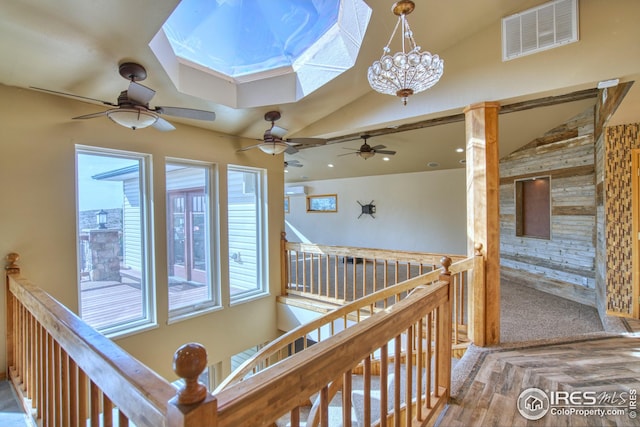 corridor with a chandelier, vaulted ceiling with skylight, and carpet