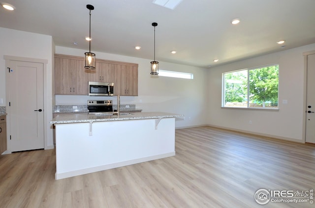 kitchen with pendant lighting, light stone countertops, a kitchen bar, and stainless steel appliances