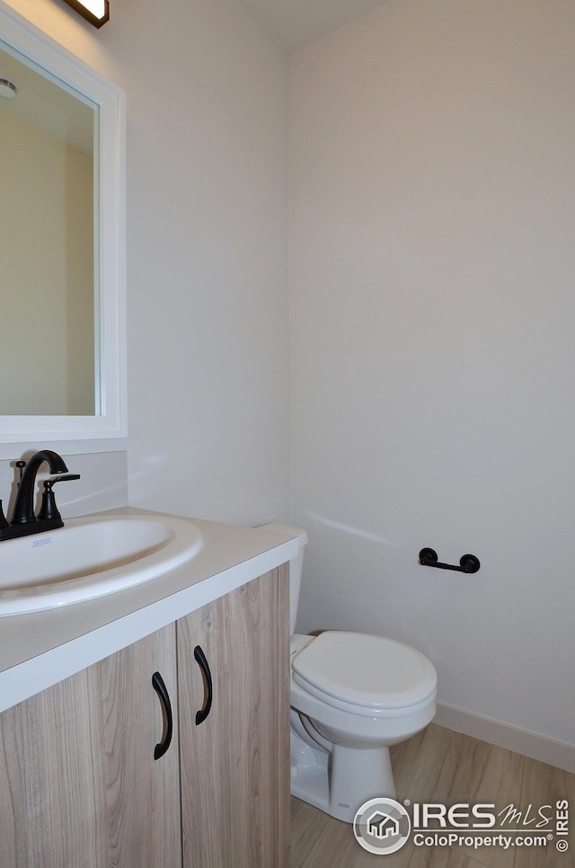 bathroom with vanity, toilet, and wood-type flooring