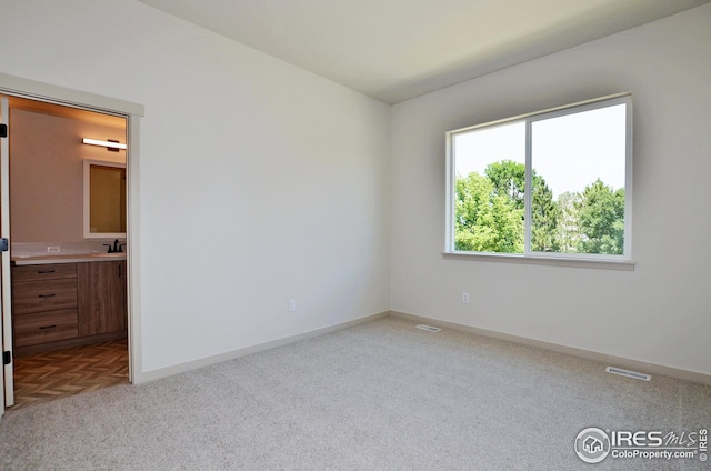 spare room featuring sink and light colored carpet