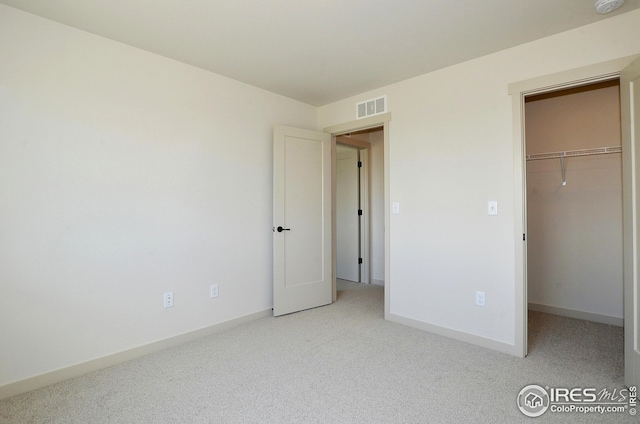 unfurnished bedroom featuring light carpet, a walk in closet, and a closet