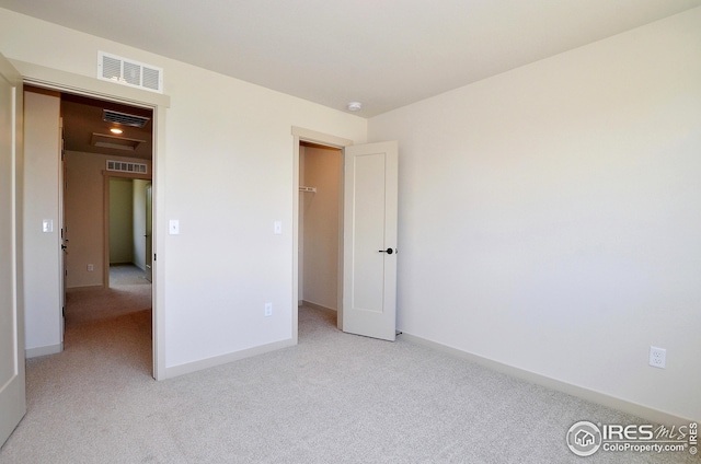 unfurnished bedroom with a spacious closet and light colored carpet