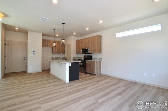 kitchen with an island with sink, a breakfast bar area, pendant lighting, light hardwood / wood-style floors, and stainless steel appliances