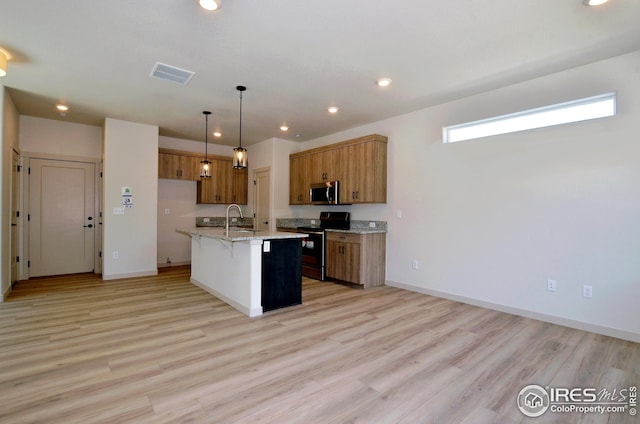 kitchen with appliances with stainless steel finishes, light hardwood / wood-style flooring, pendant lighting, and an island with sink