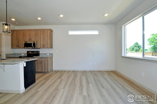 kitchen featuring appliances with stainless steel finishes, sink, light wood-type flooring, a kitchen breakfast bar, and hanging light fixtures