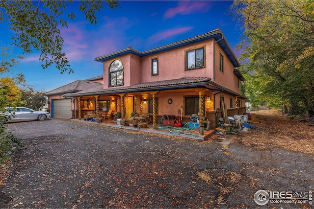 view of front of house featuring covered porch, a garage, stucco siding, and driveway