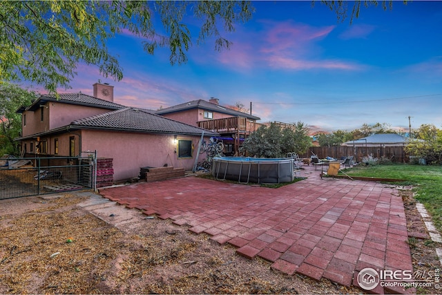rear view of house with stucco siding, a chimney, a patio area, and a fenced backyard