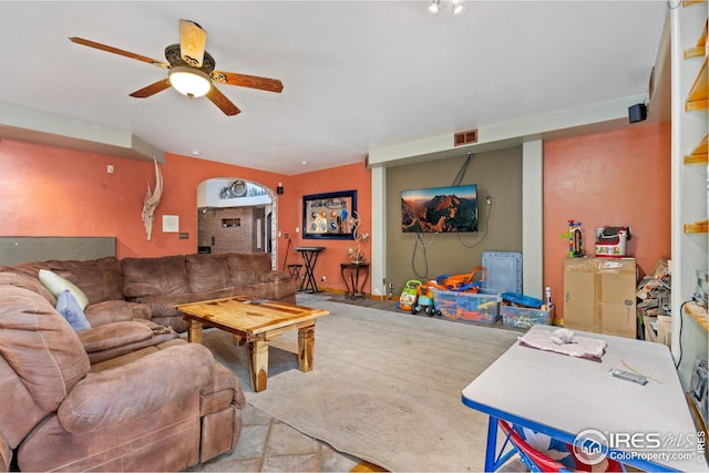 carpeted living room featuring a ceiling fan and arched walkways